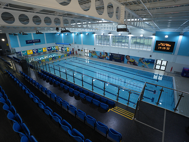A large room with an indoor swimming pool, seats overlooking the pool
