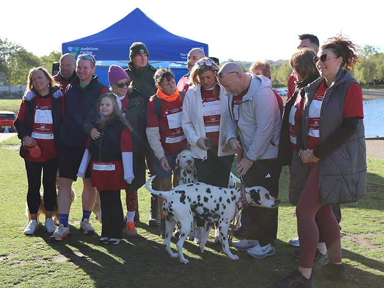 A group of people stood together with two Dalmations, a blue gazebo in the background