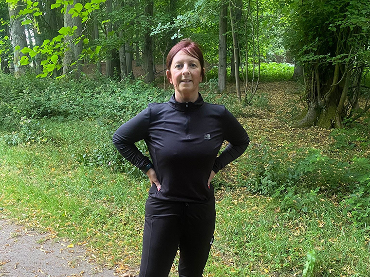 A female wearing all black stood on a footpath with trees in the background